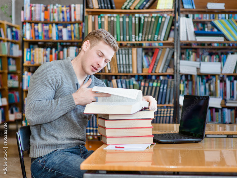 Young male student reading book in library Young male student reading book in library