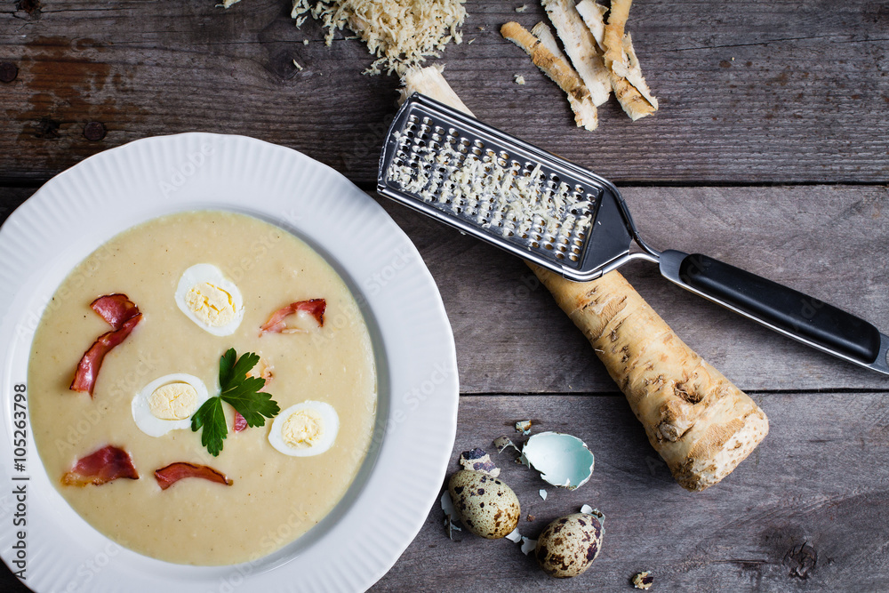 Horseradish cream soup with quail egg and black forest ham and a leaf of parsley.