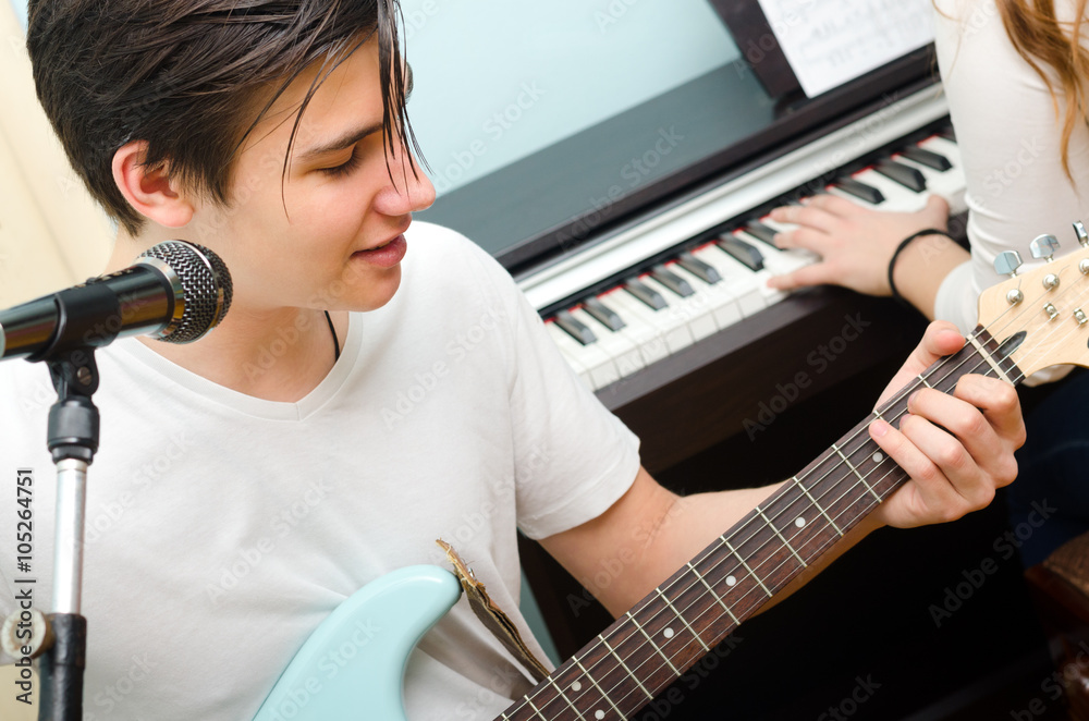 Teenage boy playing electric guitar and singing with piano Stock Photo |  Adobe Stock