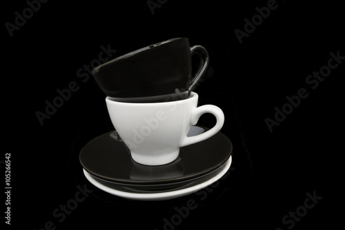 Black and White coffee cups. Two stacked black and white coffee cups and saucers. Isolated on a black background