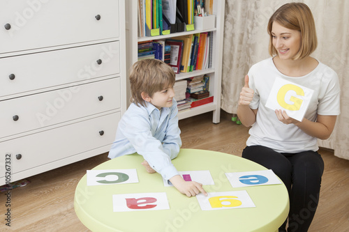 beautiful young teacher teaches letters with a cute Caucasian bo