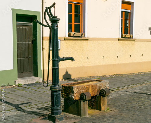 Alte Wasserpumpe Bedienung per Hand vor einer alten Hausfassade photo