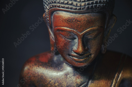 Wooden bronze buddha on black blurred background