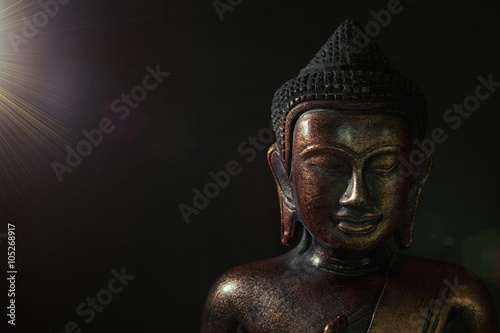 Wooden bronze buddha on black background