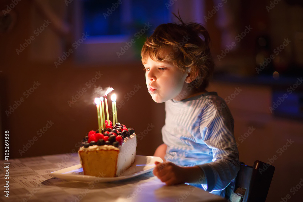 Little kid boy blowing candles on birthday cake