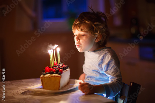 Valokuva Little kid boy blowing candles on birthday cake
