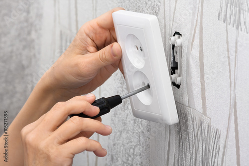 hands installing a wall power socket
