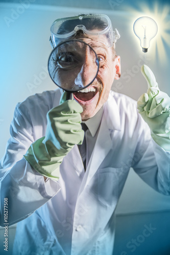 funny engineer inventor scientist looks through a magnifying glass and and raised his index finger