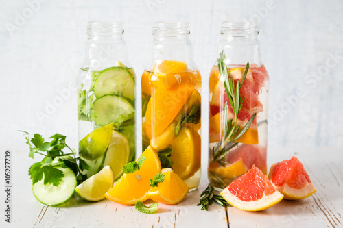 Selection of infused water in glass bottles, rustic wood background