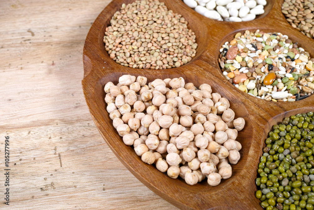 Wooden bowl of various legumes on wooden background copy space