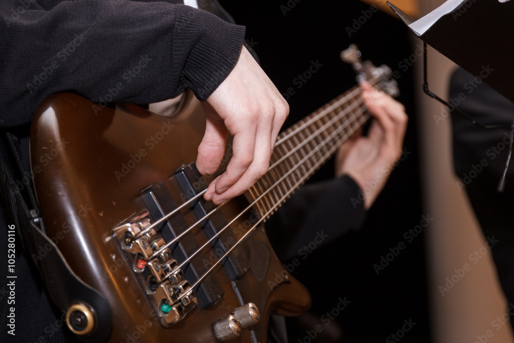 кисти рук и пальцы играют на бас гитаре