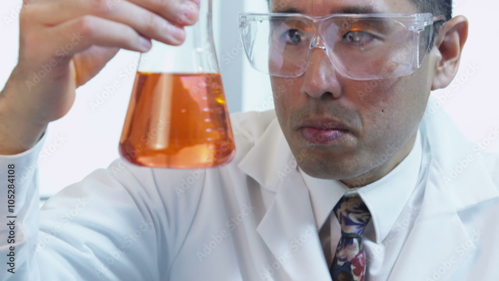 Man in science lab looking at beaker of liquid Man in science lab looking at beaker of liquid