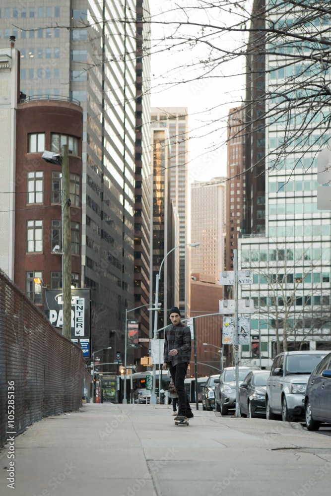 Full back figure of a skateboarder cruising down city street bef