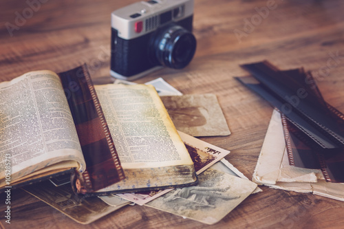 Photo of old book and camera with old photos and film strips photo