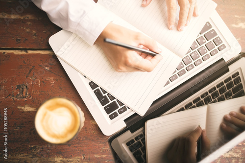 Man hands writing in the diary, coffee mug and laptop on wooden photo