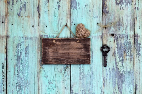 Blank rustic sign with heart and antique key hanging on teal blue wood background