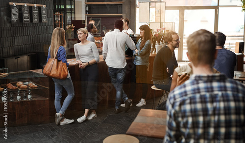 Modern coffee shop with customers standing at counter and sittin