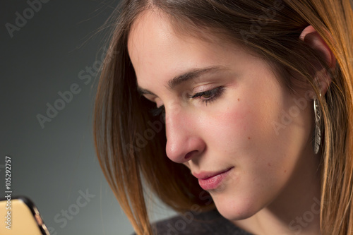 Close-up of young woman reading a message on smartphone