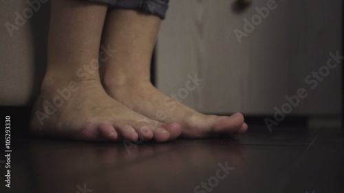 Slow motion close-up footage of feet get out of bad and hit the floor. 