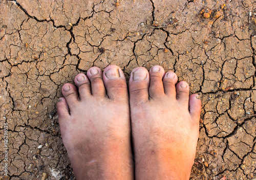 Barefoot standing on dry and cracked ground background 