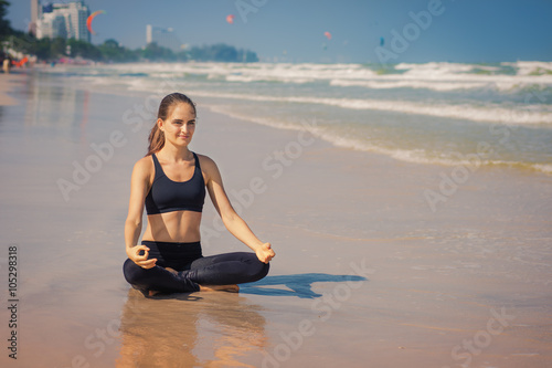 Молодая женщина занимается йогой на берегу моря