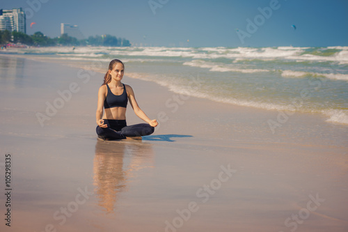 Молодая женщина занимается йогой на берегу моря