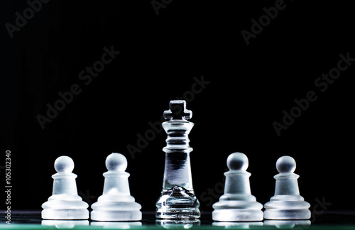 King and several pawns on chessboard in dark background. Hierarc
