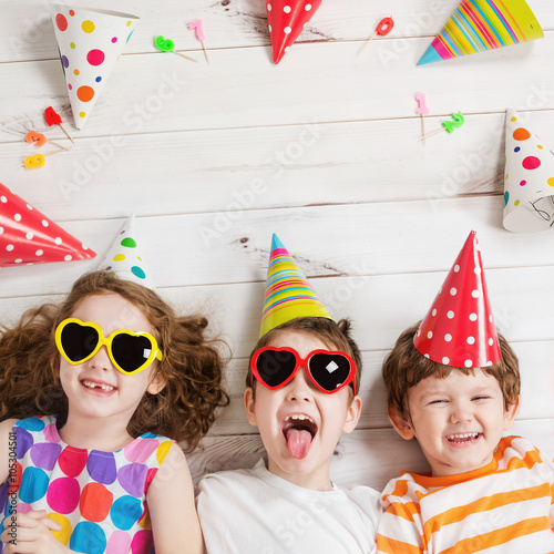 Happy child friend in carnival party, lying on a wooden floor. photo