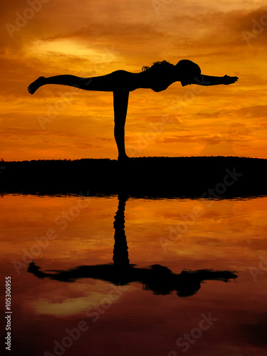 Silhouette of a beautiful Yoga woman with water reflection