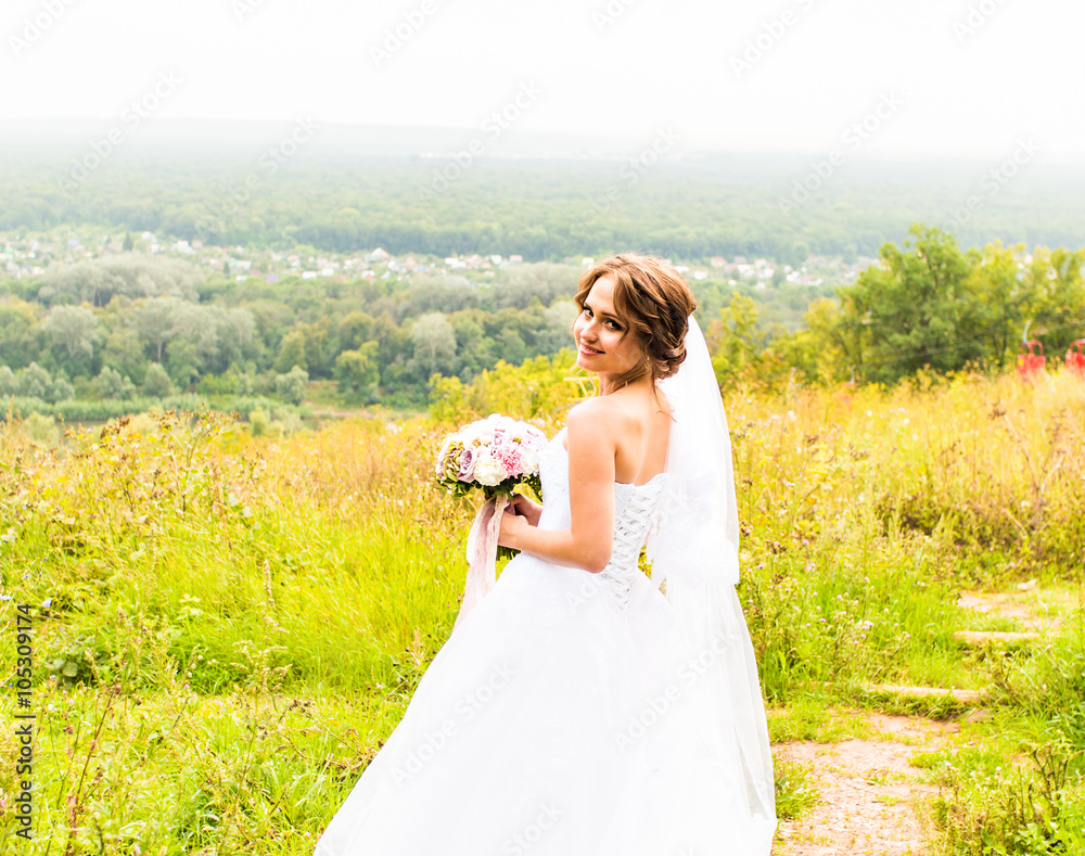 Beautiful bride with bouquet of flowers outdoor