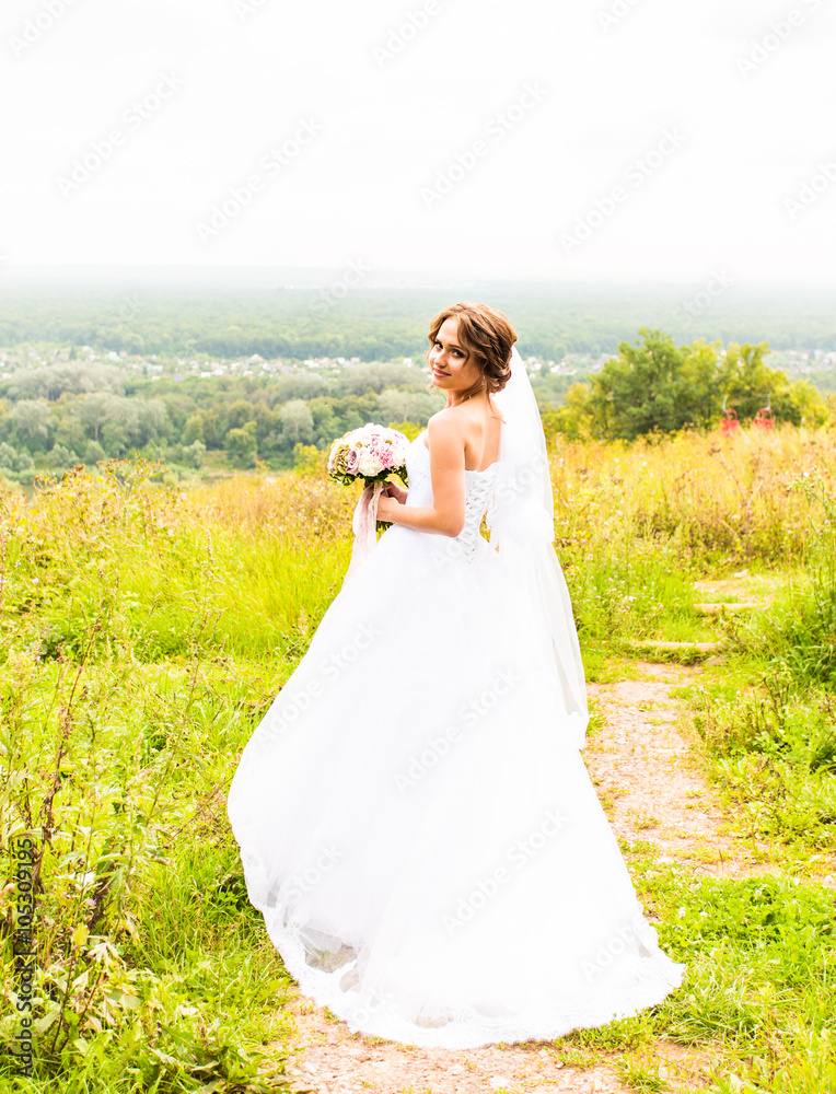 Beautiful bride girl in wedding dress  and bouquet of flowers, outdoors portrait