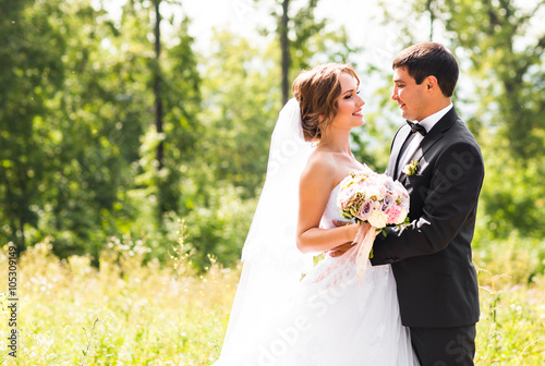 Groom and Bride in a park. Bridal wedding bouquet of flowers