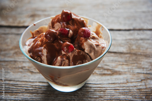 chocolate ice cream with syrup and frozen cherries