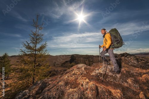 Backpacker on a high rock and looking at the big green valley © tolstnev