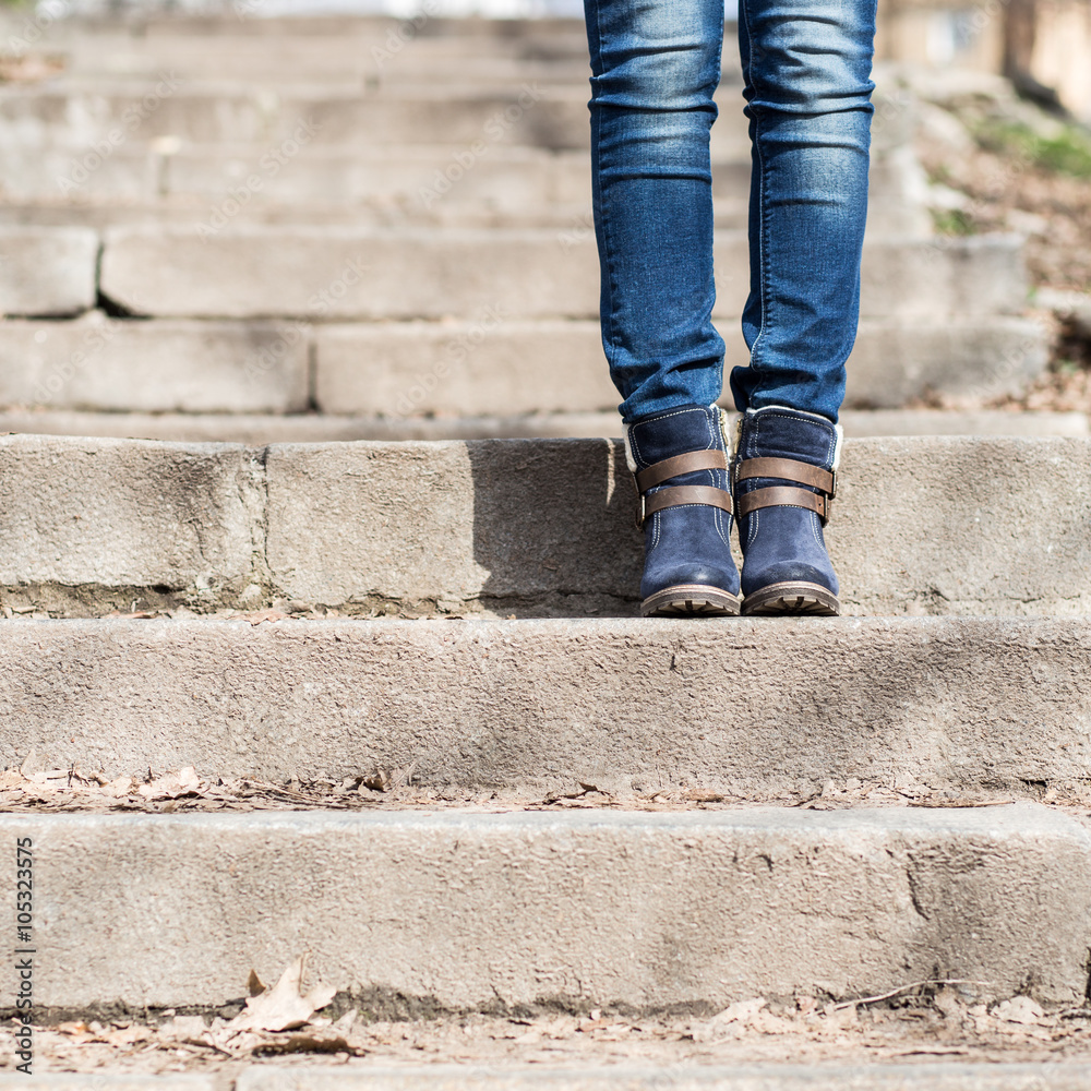 Female legs in winter boots and jeans on stairs Female legs in winter boots and jeans on stairs