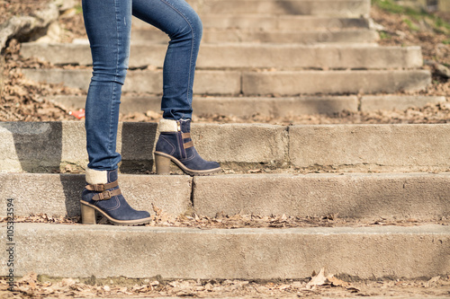 Female legs in winter boots and jeans on stairs