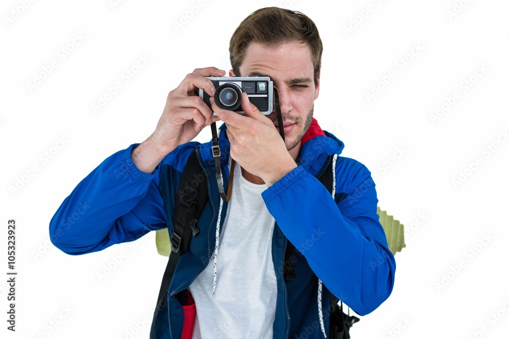 Backpacker hipster taking pictures with a retro camera against white background
