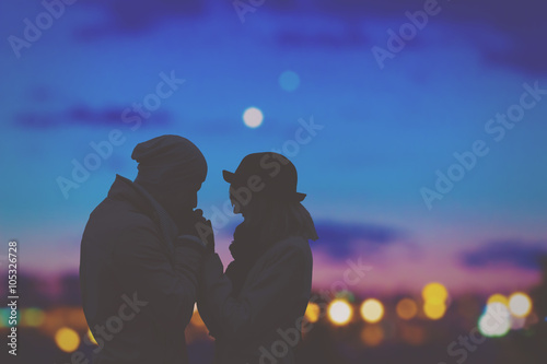 Couple in love with de-focused city lights in the background.
