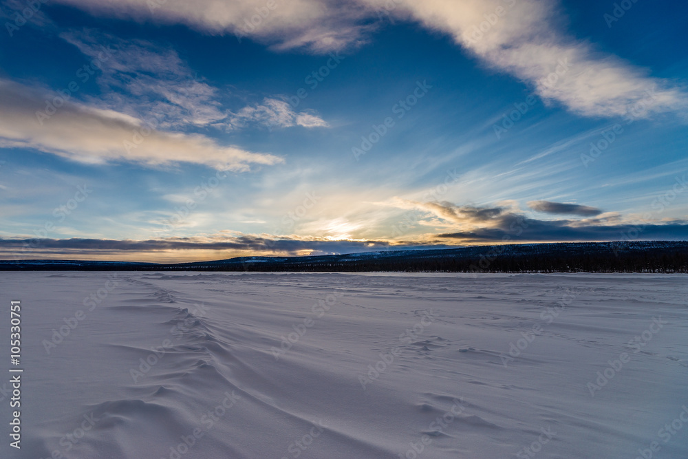 Fototapeta premium Winter landscape with forest, cloudy sky, road and snow and ice road 