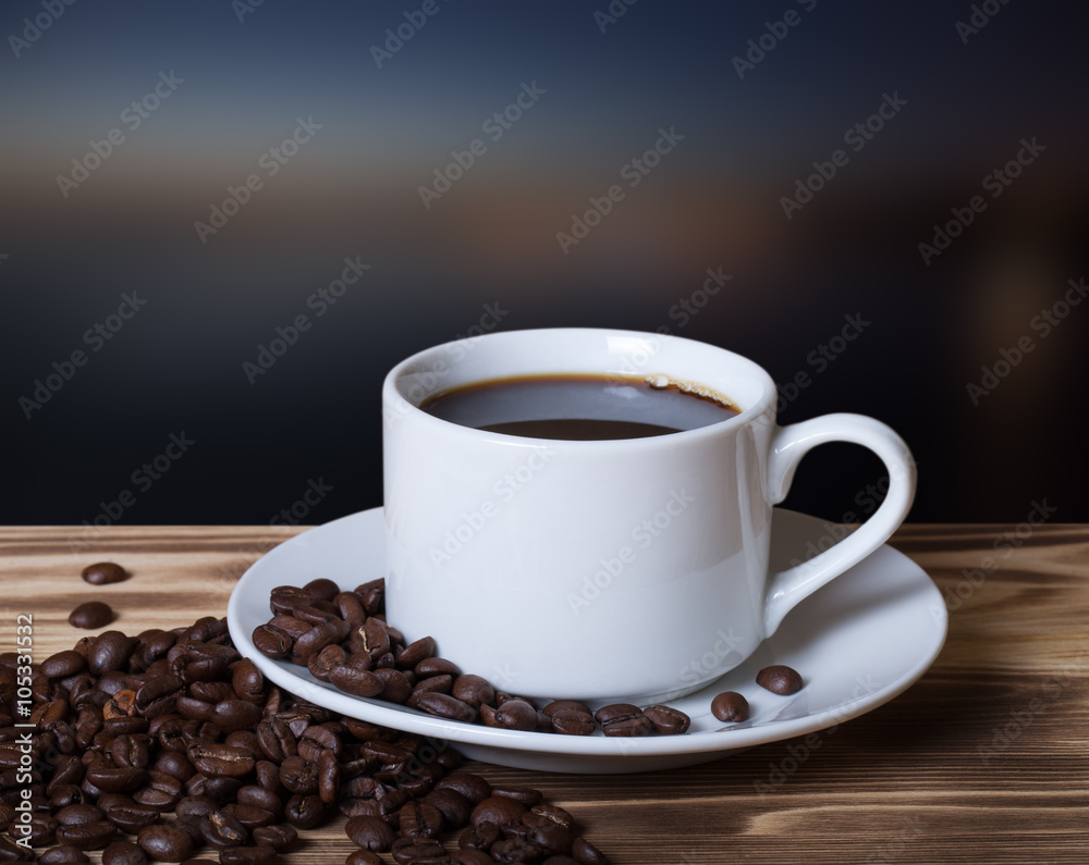 Fototapeta premium Coffee beans and coffee in white cup on wooden table opposite a