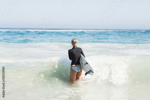 Woman with surfboard walking towards sea