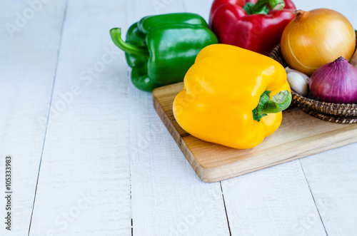 fresh yellow, red, green sweet pepper and onion in basket on woo