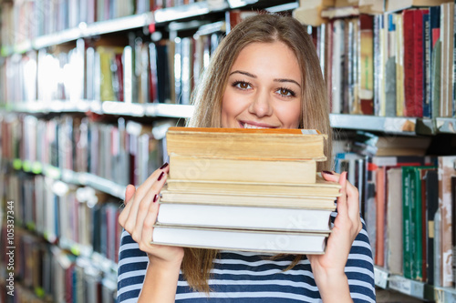 Young college woman in library holding books.