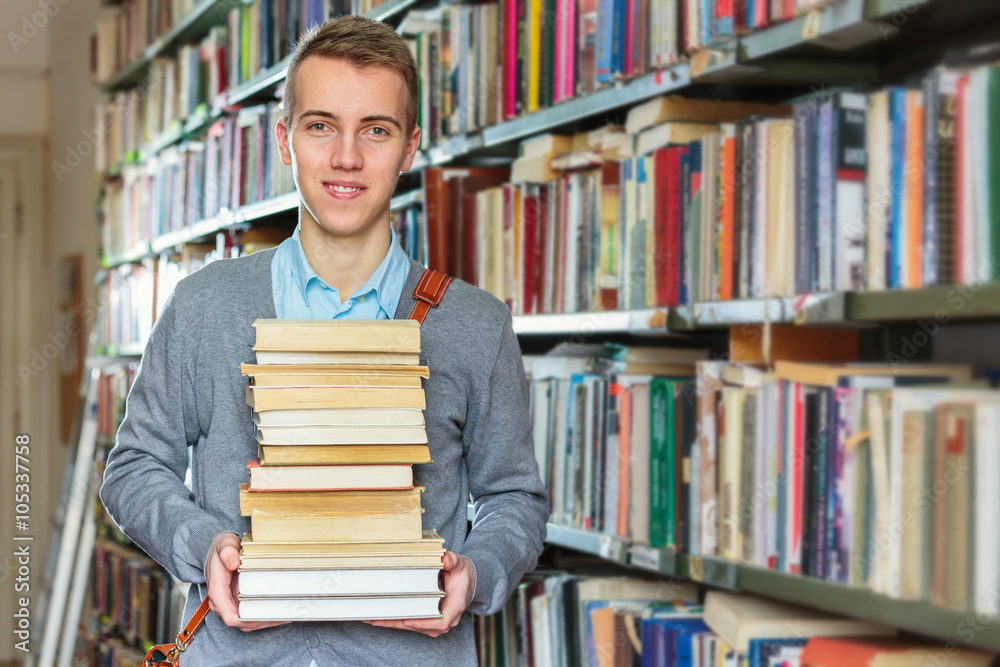 Young male student holding books at the library Young male student holding books at the library