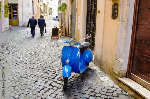 vespa parcheggiata in un vicole di Roma e coppia che è andata a fare la spesa