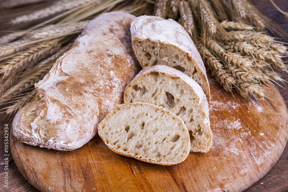 ciabatta with ears of wheat on a white wooden table