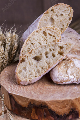 ciabatta with ears of wheat on a white wooden table