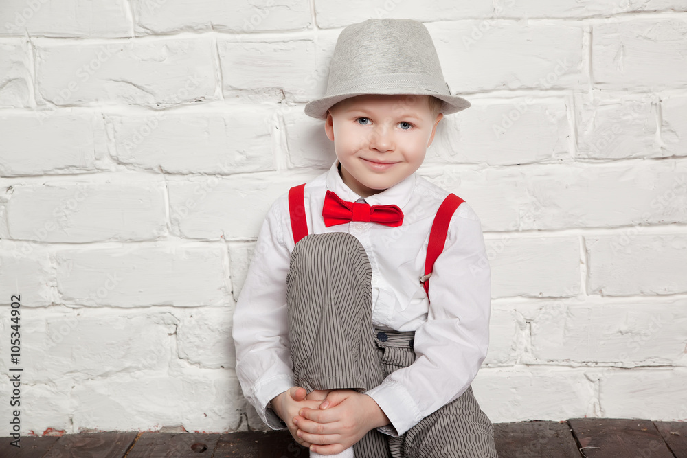 little boy wearing a red bow tie suspenders and white shirtand