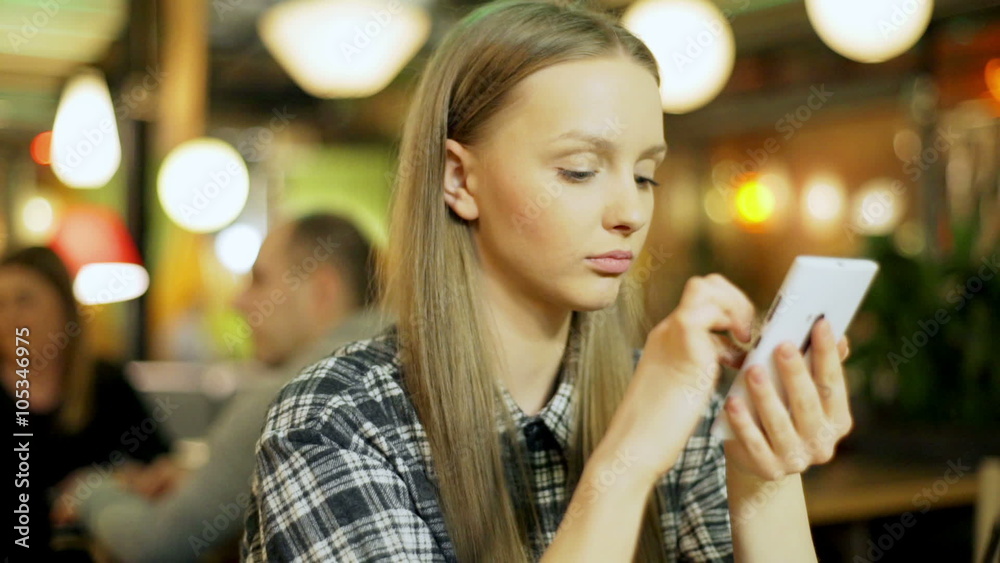Girl browsing internet on smartphone and smiling to the camera
Girl browsing internet on smartphone and smiling to the camera