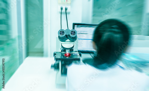 women with blue blur background and red ray use microscope for f